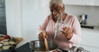 © DisobeyArt - Happy black senior woman cooking healthy food inside kitchen