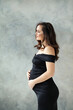 © millaf (Nemchinova) - Beautiful stylish pregnant woman in black dress relaxing on gray background portrait