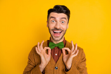 Sticker - Portrait of impressed positive guy open mouth look camera fingers touch bow isolated on yellow color background