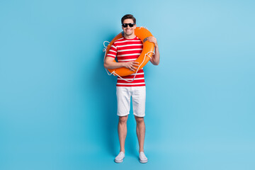 Sticker - Full length body photo man wearing orange circle chilling on beach isolated on vibrant blue color background