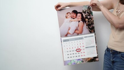 Wall Mural - A woman holds it in his hands a calendar with a family photo. 