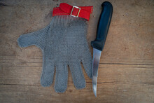 Metal Protective Glove And Kitchen Knife On Wooden Table,for Butchers Or Woodworking .