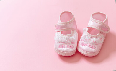 Wall Mural - It’s a girl announcement. Baby girl pink shoes on pink color background. Baby shower, christening concept.