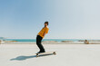 © Tadeu Dreyer/Stocksy - Young man skateboarding with a longboard in front of the beach