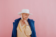 Happy smiling lady wearing trendy blue faux fur coat, yellow sweater, stylish silver wrist watch, white hat, posing on pink background. Fashion conception. Copy, empty space for text
