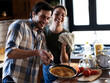 © JustLife - Boyfriend and girlfriend making pancakes at home. Young couple having fun in the kitchen