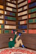 Young Guy With A Skateboard On The Background Of Books