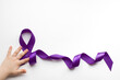 Purple ribbon with a child's hand on a white background with a place for text in honor of the day of patients with epilepsy on March 26