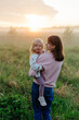 © Sergey Narevskih/Stocksy - Mother and child standing in misty field during sunset