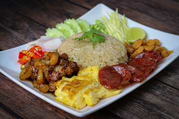 Rice seasoned with shrimp paste or rice mix slice of red onion, bean,mango, fried egg,, Thai Food on wooden background