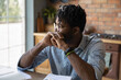 canvas print picture - Thinking by window. Pensive afro caribbean guy student hipster sit at table leaning on folded hands reflect on training task. Concentrated young black man freelancer creating idea planning future work