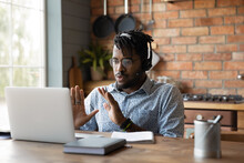 Young African Male In Headphones Engaged In Distant Learning Answer On Teacher Question At Virtual Class Held By Video Conference. Millennial Black Man Capable Expert Assist Client Online Using Laptop