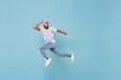 © ViDi Studio - Full length of young shocked scared frightened unshaven black african man 20s in violet t-shirt hat glasses jump high run away fast hurrying isolated on pastel blue color background studio portrait.