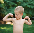 © Jakob Lagerstedt/Stocksy - Cute young boy with no shirt pretending to flex his arm muscles