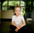© Jakob Lagerstedt/Stocksy - Handsome young boy with a mohawk haircut sitting on the floor