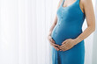 © Maki Company Limited/Stocksy - Young beautiful pregnant woman standing near window at home