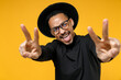 © ViDi Studio - Young joyful happy fun african american man 20s wearing stylish black hat shirt eyeglasses show close up victory v-sign gesture stretch hands to camera isolated on yellow background studio portrait
