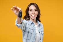 Young Smiling Happy Satisfied Excited Successful Brunette Woman 20s In Denim Shirt White T-shirt Hold In Hands Giving Car Keys Show Thumb Up Like Gesture Isolated On Yellow Background Studio Portrait.