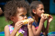 © absphotography/Stocksy - Toddler child and her older sister eating and enjoying fresh corn on a hot summer day.