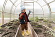 © Alina Hvostikova/Stocksy - Boy with gardening tools in hothouse