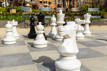 Empty park with big chess figures and empty chairs on background.Nobody playing in games.