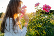 © Sergey Narevskih/Stocksy - Young woman smelling flowers in park