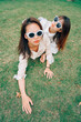 © Pansfun Images/Stocksy - Two fashion women lying on the grass