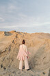 © Sergey Filimonov/Stocksy - Unrecognizable female in pink pantsuit standing on sand