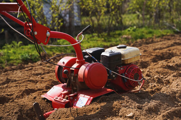 Man plows soil, land, makes garden beds with small walk-behind tractor. Spring planting of potatoes. Good harvest. Farming, self cultivation of healthy, natural eco friendly bio food and vegetables