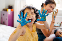 Mixed Race Child Showing Hands Covered In Paint