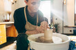 © Yakobchuk Olena - Master sitting at the potter's wheel and holding unfired clay cup