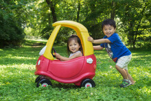 Asian Siblings Having Fun With A Toy Car On The Grass