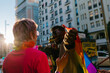 © MyMicrostock/Stocksy - Happy multiracial couple raising LGBT pride flag in street in daylight