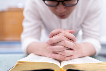 A man is reading the Holy Bible and praying in a worship room in a Christian church.