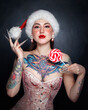Portrait of beautiful tattooed young woman in Santa hat and corset, with fancy makeup and nails