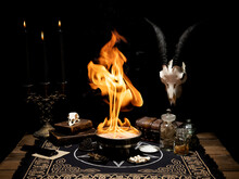 Satanic Black Magic Ritual With Fire. Animal Skulls And Candles. Antique Magic Books, Bones, Muhsrooms And Bowl On The Table. Witchcraft And Occult Concept.