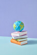 © Yaroslav Danylchenko/Stocksy - Papercraft stack of study books and Earth's globe.