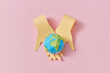 © Yaroslav Danylchenko/Stocksy - Papercraft two crossing hands are holding planet.