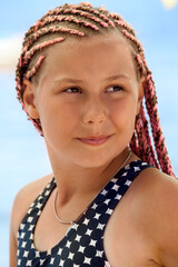 Portrait of young girl with pink dreadlocks, tanned brown skin, teenager wearing swimsuit