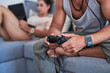 © Guille Faingold/Stocksy - Crop man playing video game on sofa