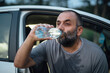 © Boris Jovanovic/Stocksy - Man Sitting In The Car, Drinking Water