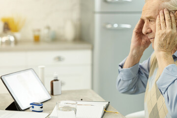 Wall Mural - Worried aged man having headache and consulting online medic