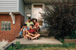 © Jessica Klaus/Stocksy - Family sitting together on front porch.