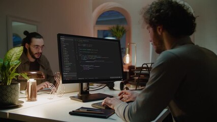 Programmers write codes on computers in semi-dark office