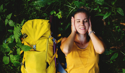 Wall Mural - top view of woman hiker lying on the ground outdoors in forest, resting.