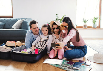 Wall Mural - Parents with small daughters indoors at home, packing for summer holiday.