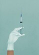 © Valeriya Simantovskaya/Stocksy - The doctor is holding a syringe. An injection with a medicine. Medical worker in white gloves.