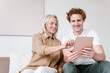 © Alina Hvostikova/Stocksy - Cheerful grandmother and grandson using tablet together