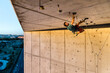 © Manu Prats/Stocksy - Active man climbing concrete building in evening