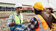 © JuYochi - A group of railway engineers discussing work outdoors on the tracks.